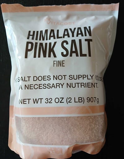 Light pink Vitacost logo on white background of salt packaging.